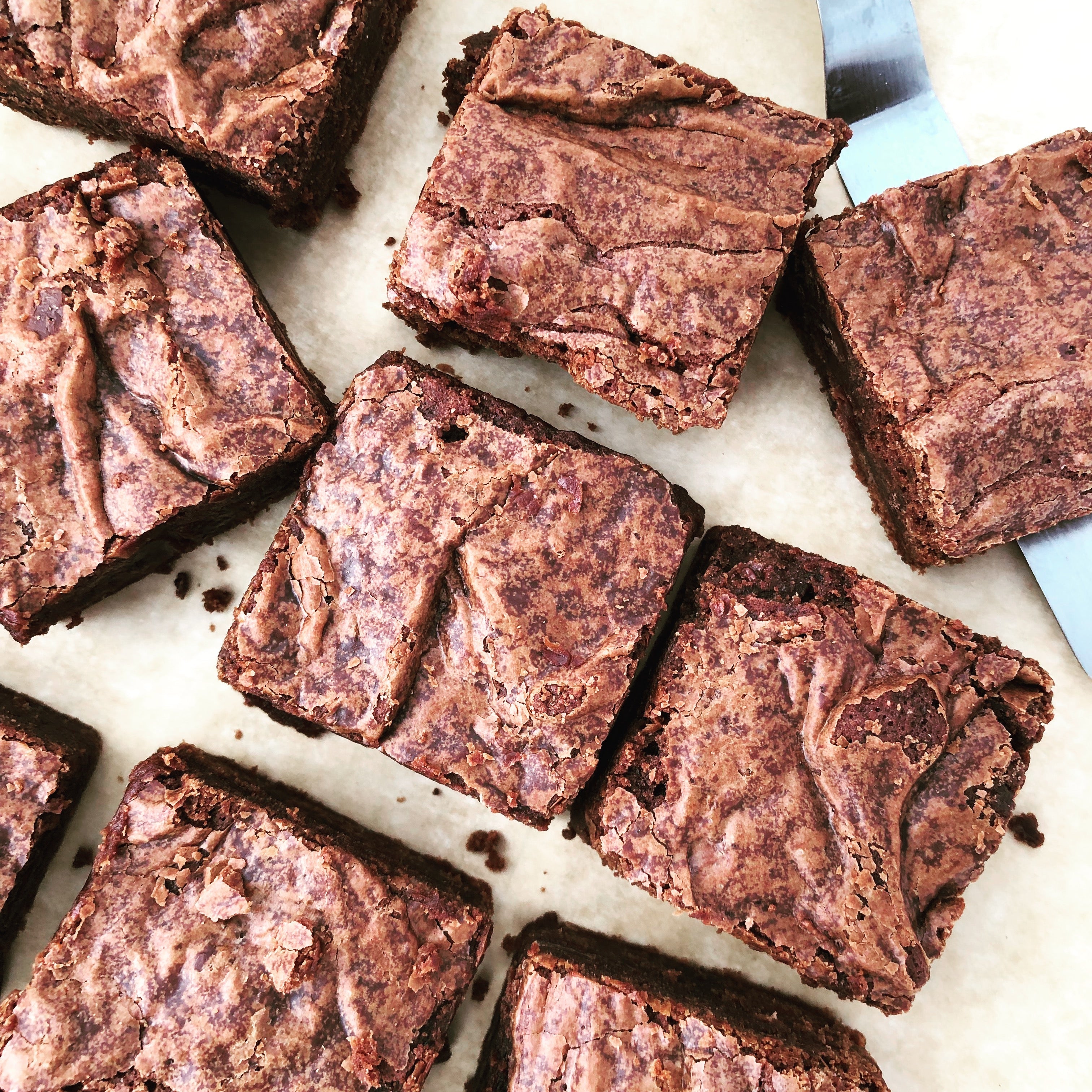 Photo of a square plastic box with 2 brownies inside. The label on top reads "Brownie bites," as well as "Scenic Made," and "small batch, big flavor." There are 2 brownies stacked outside of the box. The brownies are cut in the shape of hearts.