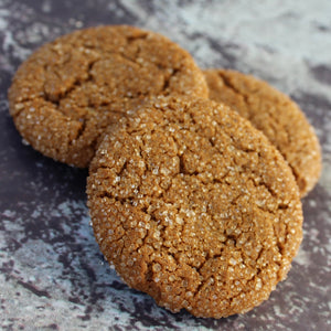 Photo of a stack of molasses cookies in a colander with a Scenic Made label on top. Label includes the words "molasses cookies" and "small batch, big flavor." There are three of the molasses cookies stacked outside of the package.