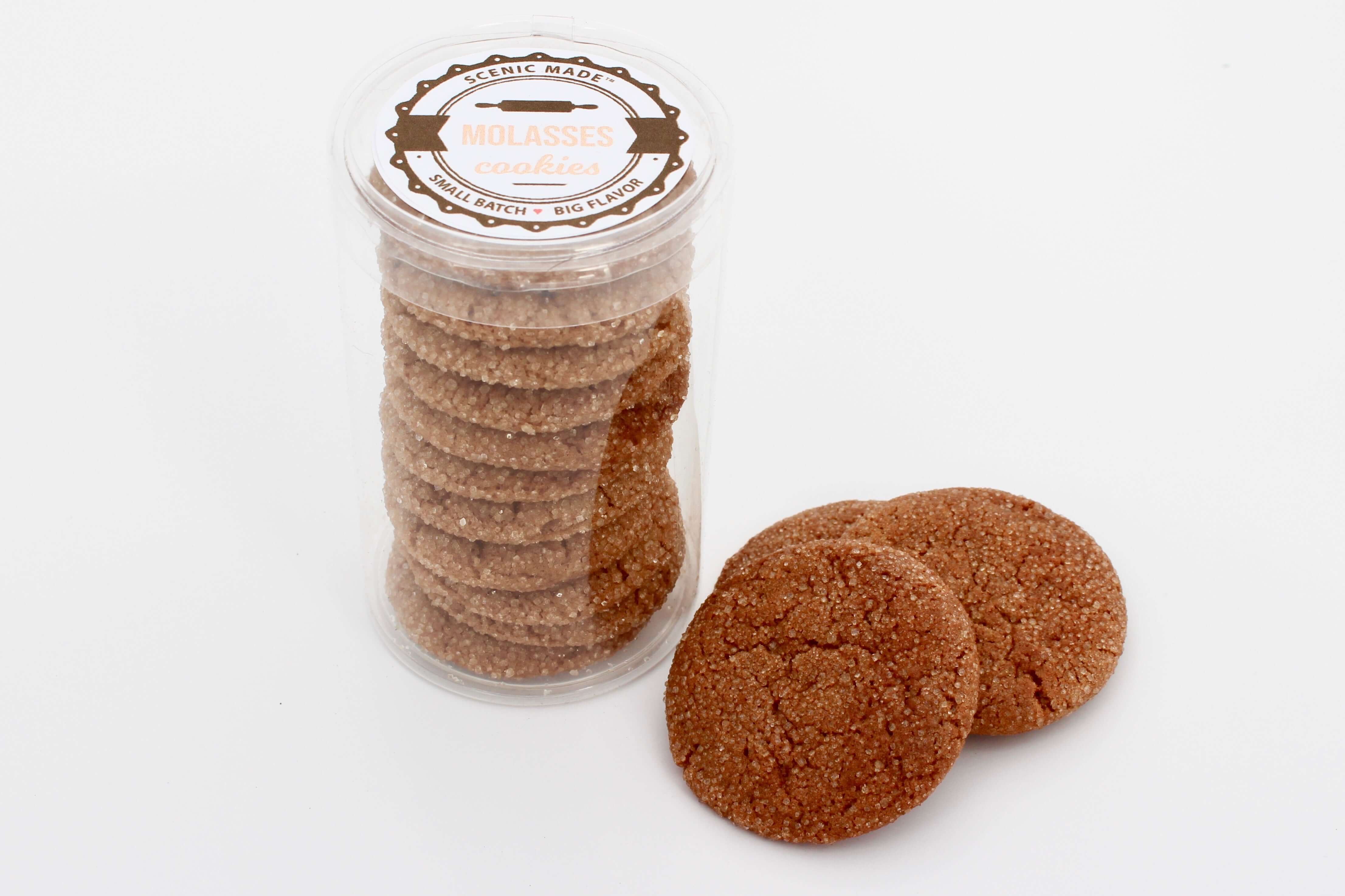 Photo of a stack of molasses cookies in a colander with a Scenic Made label on top. Label includes the words "molasses cookies" and "small batch, big flavor." There are three of the molasses cookies stacked outside of the package.