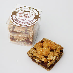 The chocolate oatmeal dream bar features on silky chocolate filling sandwiched between 2 layers of oatmeal cookie base. They are packed in a clear, square, food-safe container with an attractive label on top.