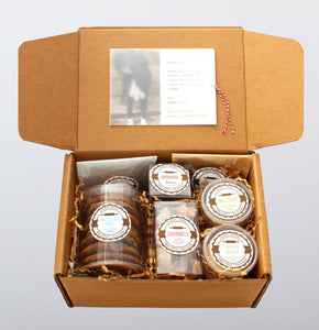 The original artisan care package. Includes separate packages of the following items: chocolate chip cookies, molasses cookies, snickerdoodles, caramels, brownie bites, granola, and cheese coins. A personalized note is put inside a translucent wrap on t
